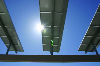 Photo of the sun shining around a solar panel.